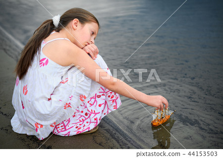 girl playing with a toy sailing ship by the river girl playing with a toy sailing ship by the river 44153503