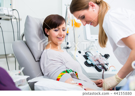 Doctors assistant checking access at female blood giver 44155880