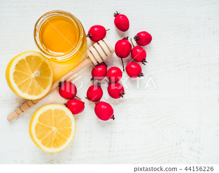 Fresh yellow lemon, jug of honey and red berries Fresh yellow lemon, jug of honey and red berries 44156226