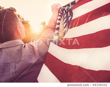 Attractive man holding waving in the wind US flag 44156332