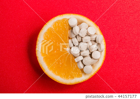 Tablets with vitamins in an orange slice on a red Tablets with vitamins in an orange slice on a red 44157177