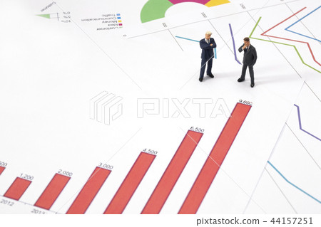Miniature businessman with graphs Miniature businessman with graphs 44157251