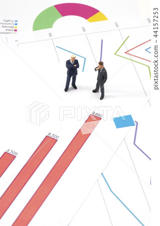 Miniature businessman with graphs Miniature businessman with graphs 44157253