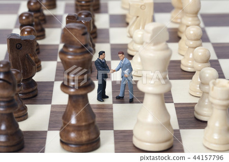 Miniature businesspeople shaking hands on a chessboard 44157796