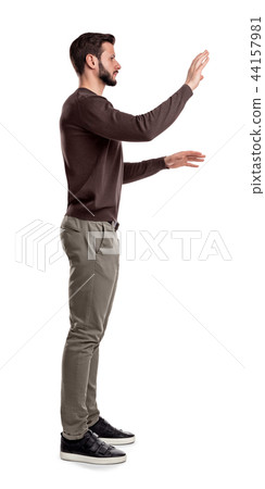 A bearded man in casual clothes stands still in a side view and used both hands to touch invisible A bearded man in casual clothes stands still in a side view and used both hands to touch invisible 44157981