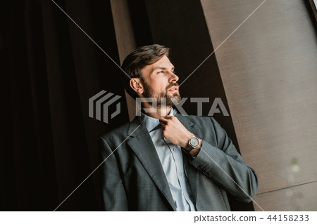 Pensive executive is fixing collar in office 44158233