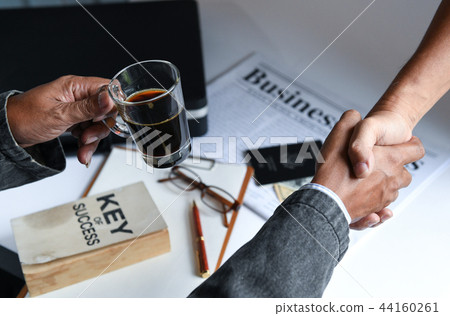 Businessmen holding coffee cup are shake hands. Businessmen holding coffee cup are shake hands. 44160261