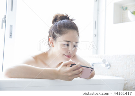 看智能手機的婦女在衛生間裡 看智能手機的婦女在衛生間裡 44161417