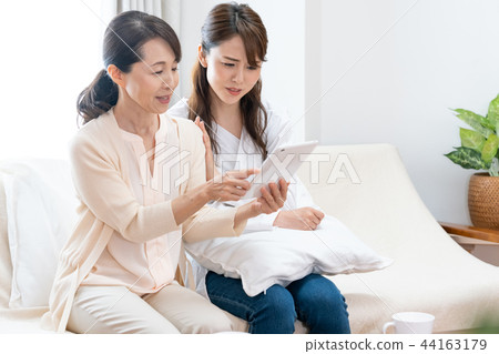 Mother and daughter looking at the tablet 44163179