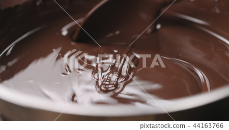 closeup stirring melted dark chocolate with spoon closeup stirring melted dark chocolate with spoon 44163766