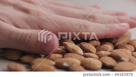 closeup man hand laying roasted almonds on paper closeup man hand laying roasted almonds on paper 44163979