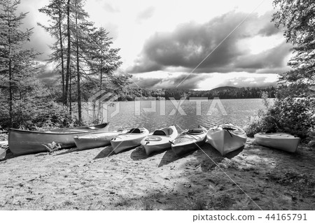 Kayaks and a canoe by the Indian lake 44165791