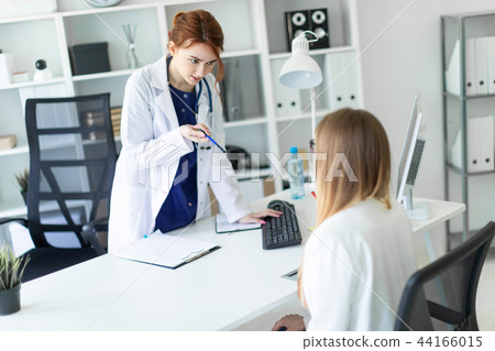 A beautiful young girl in a white robe is standing near a computer desk in the office and 44166015