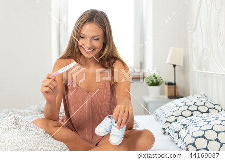 Woman holding pregnancy test in happiness Woman holding pregnancy test in happiness 44169087
