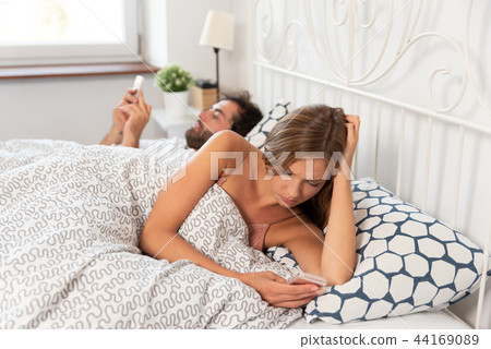 Young couple with smartphones in their bed 44169089