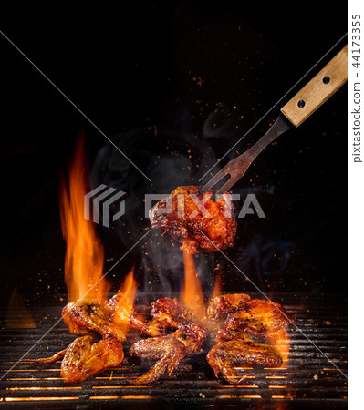 Chicken legs and wings on the grill with flames Chicken legs and wings on the grill with flames 44173355