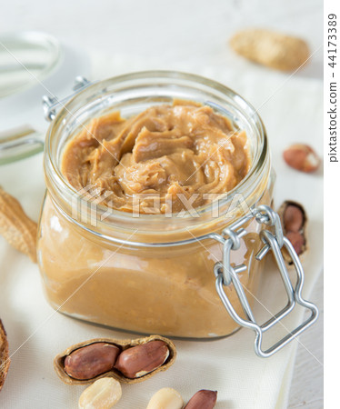 Glass jar with peanut butter on wooden background 44173389
