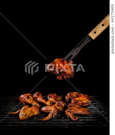 Chicken legs and wings on the grill with flames 44173409