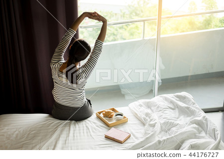 Attractive asian woman stretch oneself awaking on the bed room. 44176727