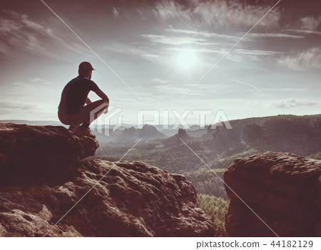 Hiker in black on rocky peak. Daybreak in rocks 44182129