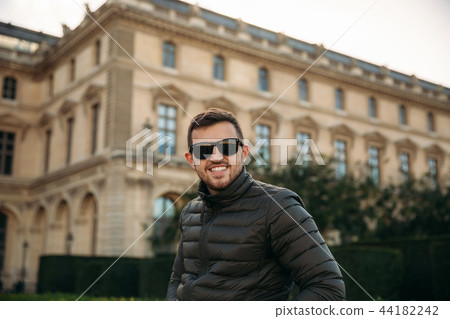 Handsome man in a khaki jacket and sunglasses is sitting on bard. Guy smile and have rest. tourits Handsome man in a khaki jacket and sunglasses is sitting on bard. Guy smile and have rest. tourits 44182242