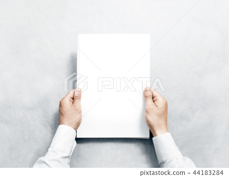 Hand holding white journal with blank cover mockup. 44183284