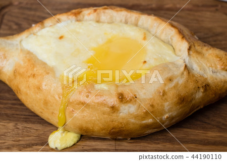 Adjarian khachapuri in restaurant on wooden plate. Adjarian khachapuri in restaurant on wooden plate. 44190110