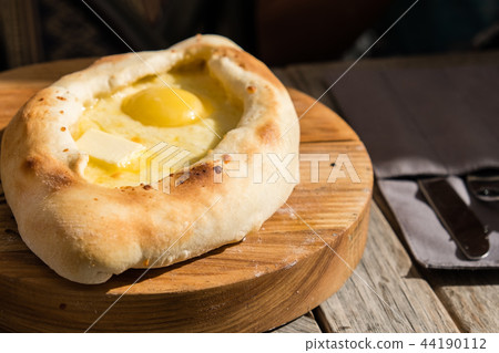 Adjarian khachapuri in restaurant on wooden plate. Adjarian khachapuri in restaurant on wooden plate. 44190112