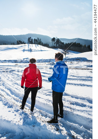 A rear view of senior couple runners standing in winter nature, resting. A rear view of senior couple runners standing in winter nature, resting. 44194477