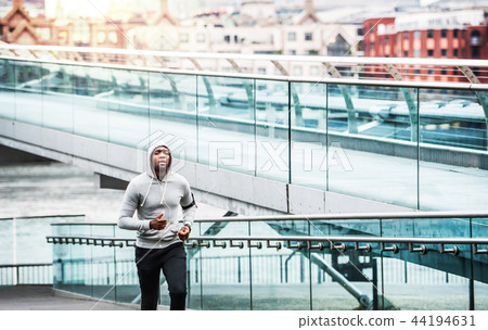 Young sporty black man runner running on the bridge outside in a city. 44194631