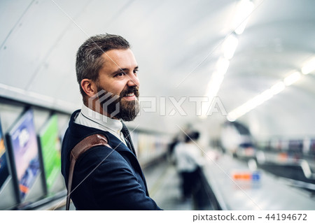 Hipster businessman using escalator in subway, travelling to work. 44194672