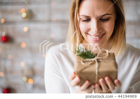 A young woman holding wrapped Christmas present. A young woman holding wrapped Christmas present. 44194909