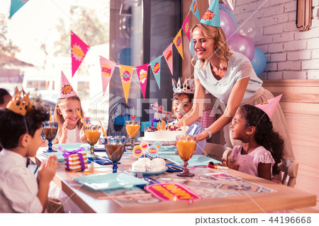 All children smiling while kind mother bringing birthday cake 44196668