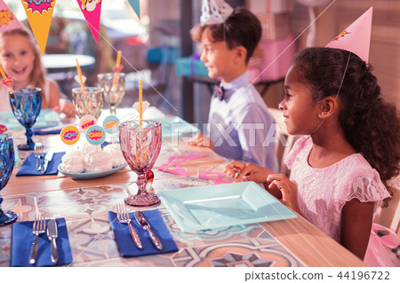 Relaxed kids smiling while sitting at the table together 44196722