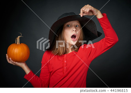 Surprised girl in a black hat holding pumpkin 44196815