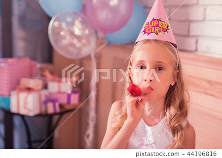 Little girl looking cute while blowing her party horn 44196816