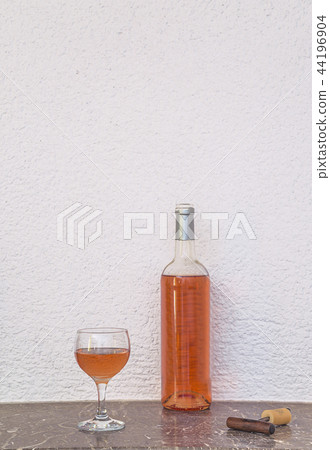Glass of pink wine and opened bottle  44196904