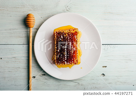 Honeycomb on white plate with honey dipper Honeycomb on white plate with honey dipper 44197271