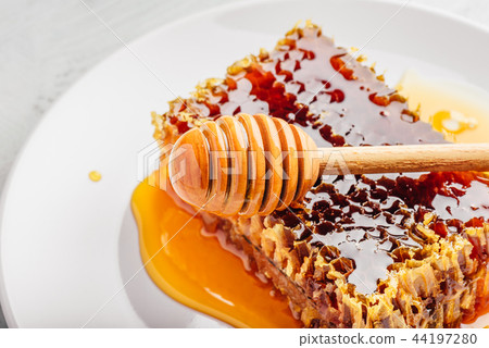 Honeycomb on plate with honey dipper 44197280