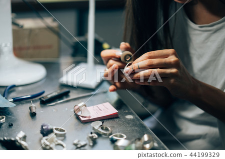 The girl works on a jewelry in the workshop The girl works on a jewelry in the workshop 44199329