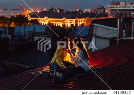 Loving couple is sitting on the roof of the house. 44199337