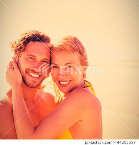 Portrait of smiling couple embracing at beach 44203357