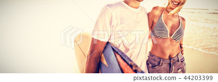 Portrait of happy young couple wearing sunglasses at beach 44203399