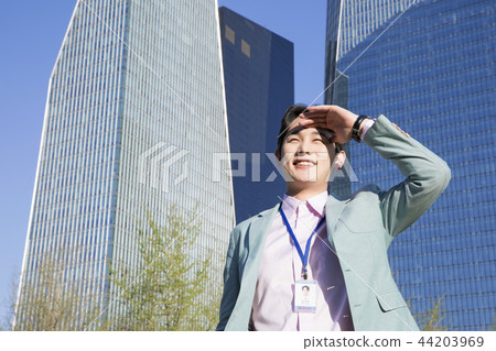 Cheerful young businessman walking in park near office building in the background. Spend time in park with collegue near office. 290 44203969