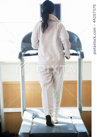 Rear view of a woman riding a running machine at the gym 44207379