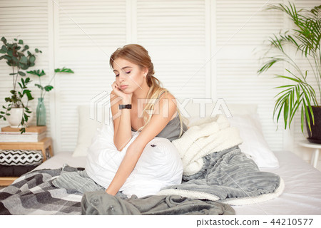Caucasian sleepy young attractive woman feeling drowsy after woke up, sits on the bed having bad Caucasian sleepy young attractive woman feeling drowsy after woke up, sits on the bed having bad 44210577