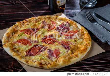 The guy cuts pizza on a wooden table The guy cuts pizza on a wooden table 44211122