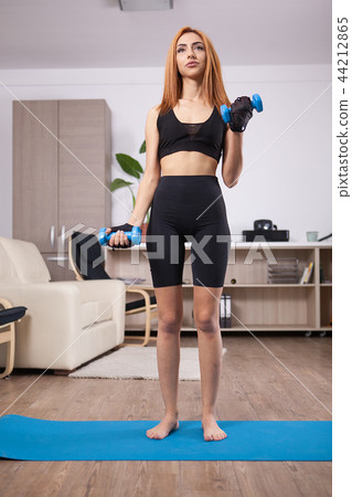 Fit girl doing front biceps curls during her home arms training Fit girl doing front biceps curls during her home arms training 44212865