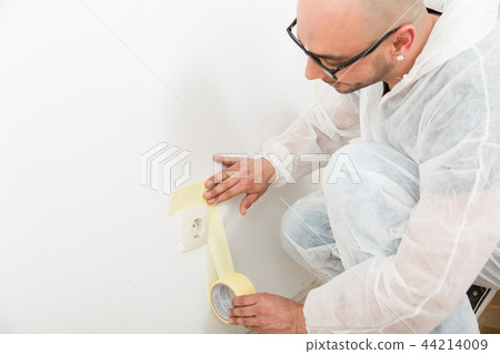 Painter sticking the tape near the plug 44214009