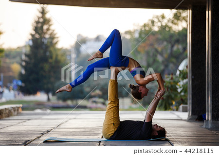 Young man and woman practicing acro yoga on street 44218115
